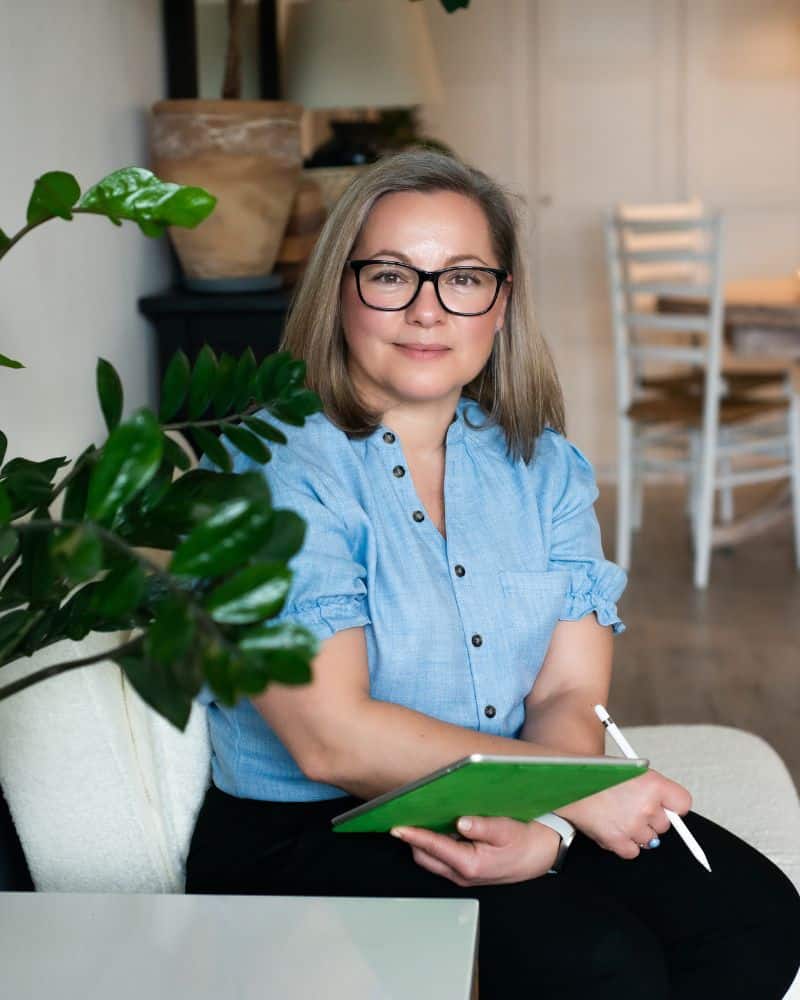 Hypnotherapist Joanna Kudzielka sitting with an iPad and pen, ready to support a client during a consultation